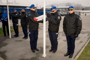 policjanci stoją przy maszcie, w rękach mają flagę RP