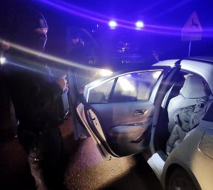 policjanci stoją przy samochodzie z nielegalnymi imigrantami
