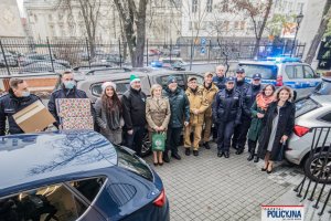 policjanci, strażnicy graniczni, strażacy oraz inne osoby stoją przed szpitalem na parkingu z darami