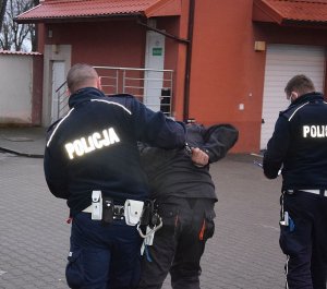 dwaj policjanci prowadzą zatrzymanego mężczyznę