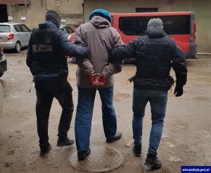 dwaj policjanci prowadzą zatrzymanego mężczyznę