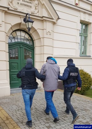 dwaj policjanci prowadzą zatrzymanego mężczyznę