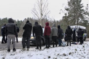 Osoby stoją przy drodze, przed nimi stoi radiowóz