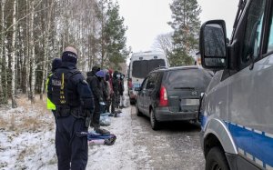 policjanci i zatrzymani mężczyźni na poboczu drogi, na drodze stoją radiowozy policyjne i samochód osobowy