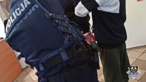 policjanci zakładają kajdanki zatrzymanemu
