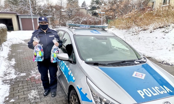 Policjantka, która stoi przy radiowozie i trzyma w rękach Sznupki