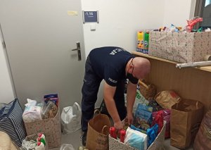 Policjant pakuje do kartonów zebrane dary dla zwierząt