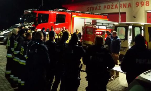 policjanci i strażacy przygotowują się do akcji poszukiwawczej, w tle widać radiowozy i wykorzystywane do działań pojazdy