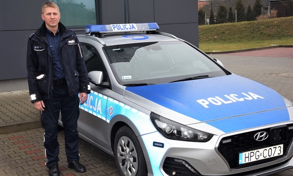 umundurowany policjant stojący przy radiowozie