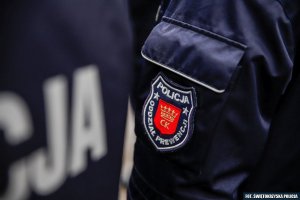 Granatowa naszywka z białymi napisami: Oddział Prewencji Policji, w środku z czerwonym wypełnieniem i żółtymi literkami CK z koroną:  na rękawie policyjnego munduru