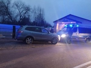 policjanci stoją przy aucie cywilnym - przed nim zaparkowany jest policyjny furgon