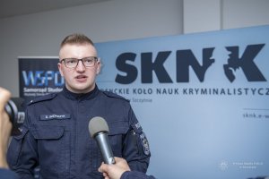 umundurowany policjant stoi przed mikrofonem