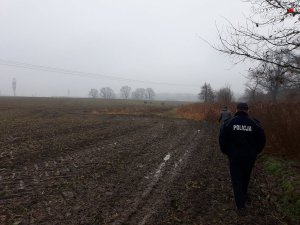 policjant przemieszczający się przez pole rolne