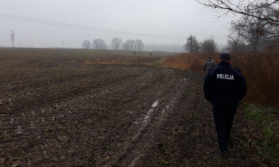 policjant przemieszczający się przez pole rolne