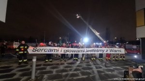 strażacy trzymają transparent z napisem sercami i głowami jesteśmy z wami