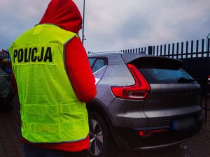 policjant w żółtej kamizelce z napisem policja w tle samochód osobowy