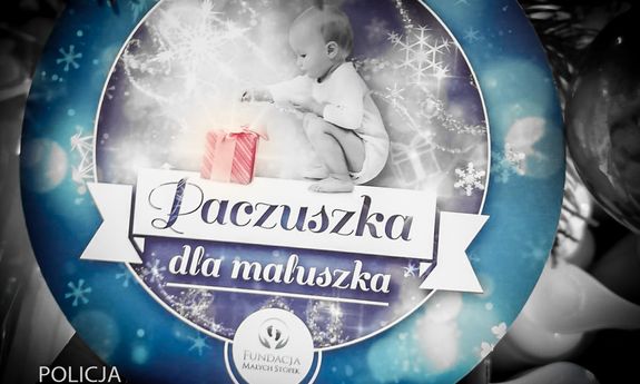 napis na plakacie paczka dla maluszka, nad napisem niemowlę siedzi przy prezencie