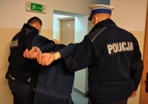 policjanci trzymają zatrzymanego mężczyznę