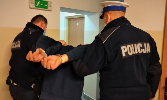 policjanci trzymają zatrzymanego mężczyznę