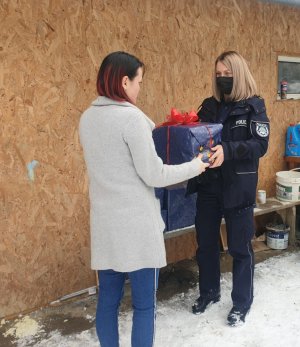 Umundurowana policjantka przekazuje świąteczną paczkę kobiecie