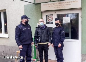 Policjanci stojący z mężczyzną przed budynkiem