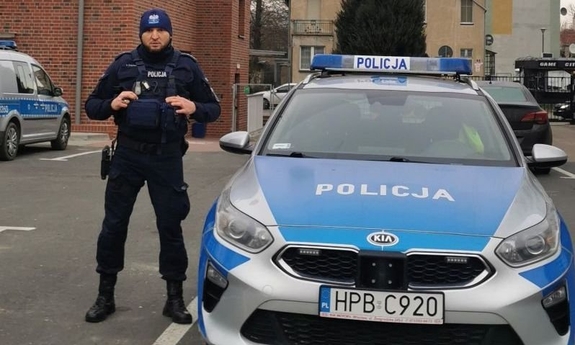 policjant stoi przy radiowozie