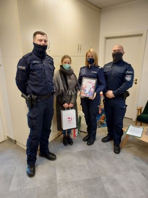 umundurowani policjanci przekazują paczki świąteczne dla dzieci z hospicjum