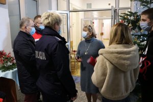 policjanci stoją w budynku hospicjum z prezentami dla pensjonariuszy