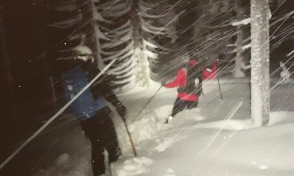 noc, ciemno, osoby idą w głębokim śniegu, oświetlają drogę przed sobą latarkami na głowie, pada śnieg