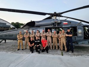 Grupowe zdjęcie funkcjonariuszy policji i strażaków przed śmigłowcem Black Hawk