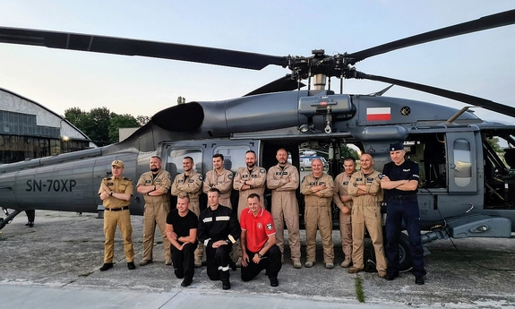 Grupowe zdjęcie funkcjonariuszy policji i strażaków przed śmigłowcem Black Hawk