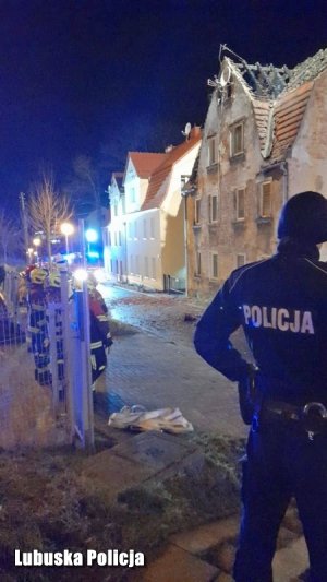 Policjant stoi przodem do kamienicy