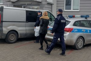 policjanci prowadzą kobietę do samochodu