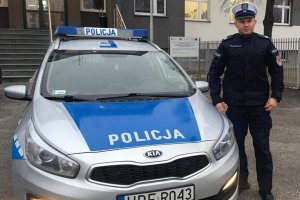 policjant stoi przy radiowozie