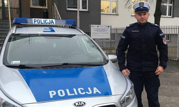 policjant stoi przy radiowozie