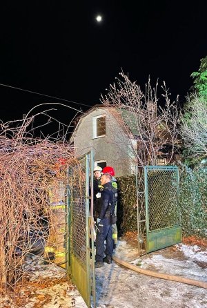 stojący w bramie policjant i strażacy