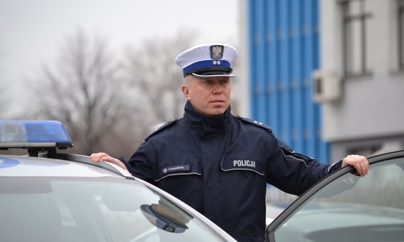 policjant stoi przy radiowozie