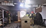 Funkcjonariusze straży pożarnej w pomieszczeniu, które się paliło