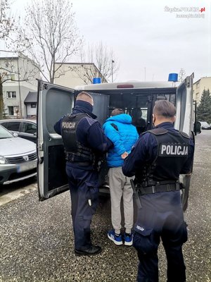 policjanci prowadzą zatrzymanego do furgonu policyjnego