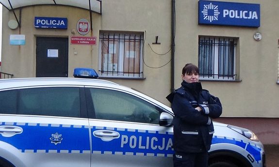 Umundurowana policjantka stojąca przed radiowozem