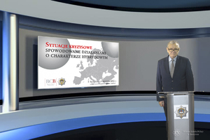 mężczyzna przedstawia slajd w prezentacji, na czerwono sytuacje kryzysowe, pod spodem na szaro spowodowane działaniami o charakterze hybrydowym