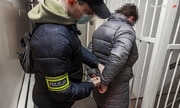 policjant zakłada kajdanki na ręce zatrzymanej kobiecie