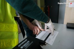 Zbliżenie na ręce podczas pobierania przez technika kryminalistycznego odbitek palców zatrzymanego mężczyzny