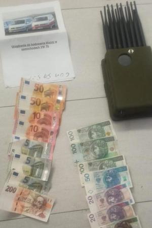 urządzenie elektroniczne i rozłożone banknoty w nominale 100, 50, 20 i 10 złotych oraz banknoty euro w nominale 50, 200, 10 i 5 leżą rozłożone na podłodze. Obok leży instrukcja od urządzenia elektronicznego