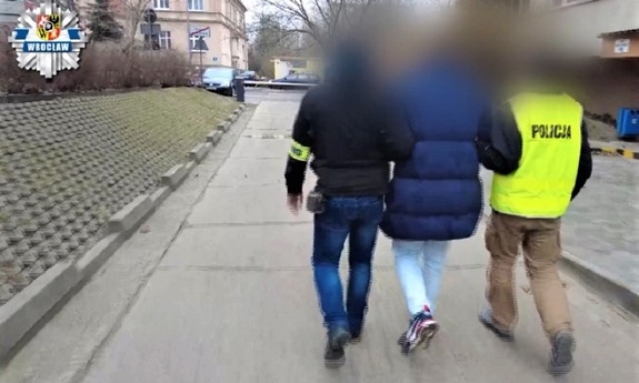 dwóch policjantów prowadzi zatrzymanego mężczyznę