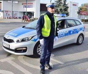 umundurowany policjant ruchu drogowego stoi przed radiowozem