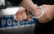 Policjant zakłada kajdanki na dłoń zatrzymanej osoby
