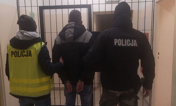 dwaj policjanci z zatrzymanym mężczyzną zakutym w kajdanki