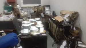 zdjęcie przedstawia odzyskane skradzione przedmioty, garnki, fotele, szklanki, przedmioty ułożone są na podłodze oraz stolach w  pomierzeniu biurowym