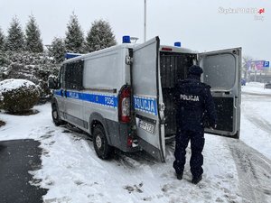 umundurowany policjant stoi przed radiowozem